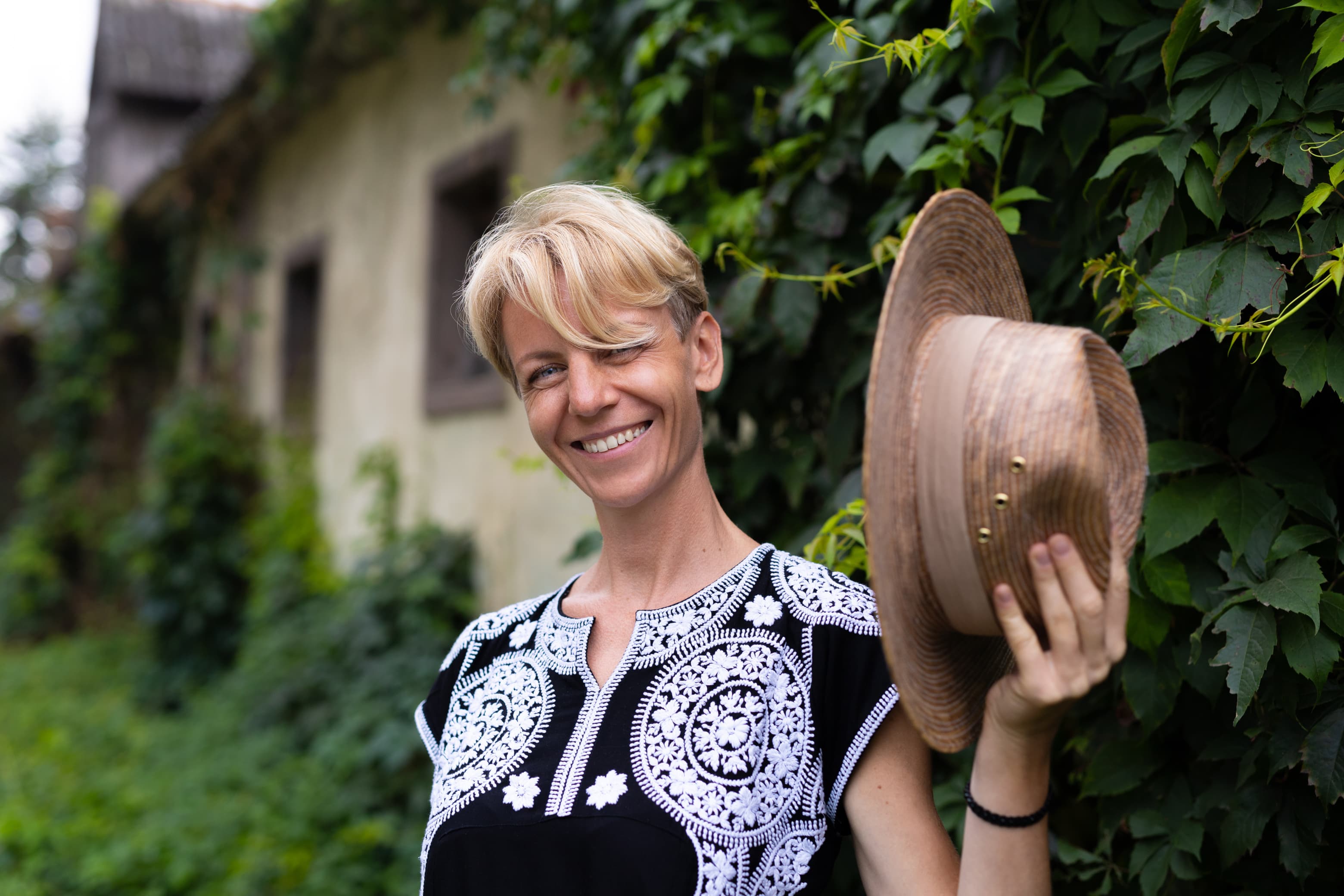 Kobieta z kapeluszem — portret plenerowy, naturalny uśmiech, sesja portretowa KLEYNOT